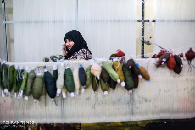 Hosseini is talking on the phone with one of her trainees in the carpet weaving workshop.
