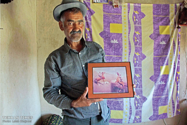 Avaz is posing in front of the camera holding the photo of his favorite horse he had to sell due to financial problems.
