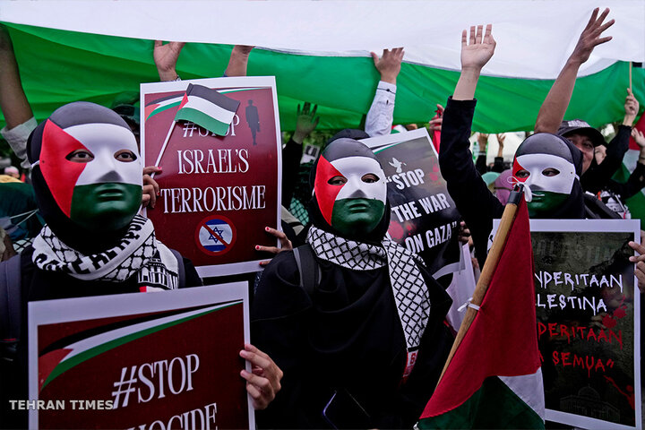 Protesters wearing masks with the colours of Palestinian flag hold posters during a rally in support of the Palestinians in Jakarta. [Dita Alangkara/AP Photo]
