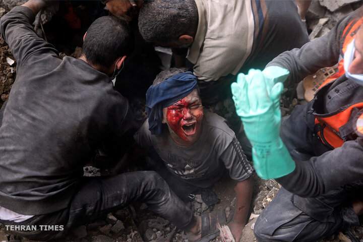 An injured Palestinian boy cries as rescuers try to pull him out of the rubble of a destroyed building following an Israeli air strike in the Bureij refugee camp. [Mohammed Dahman/AP Photo]
