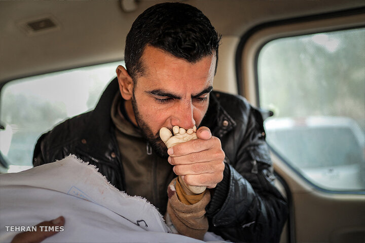 A Palestinian kisses the foot of a child, killed in Israeli strike, at the Nasser hospital in Khan Younis. [AFP]
