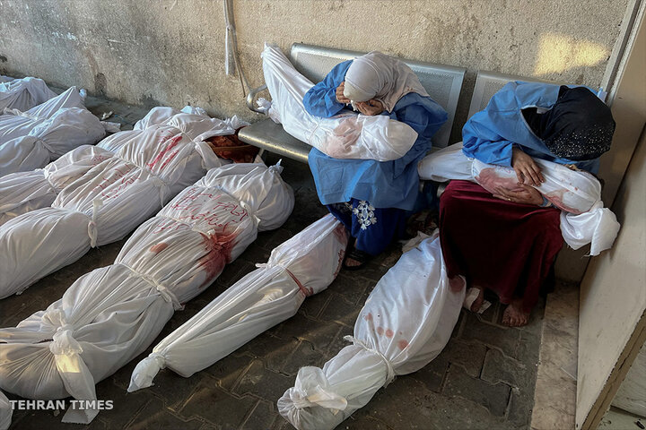 Palestinian women mourn as they hold the bodies of children killed in Israeli strikes, at the Indonesian Hospital in northern Gaza. [Fadi Alwhidi/Reuters]
