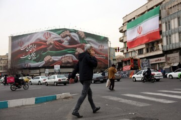 Iranians walk next to a billboard reading “Iran is our Homeland”at Enqelab Square, Tehran, Iran, Jan. 13, 2026.