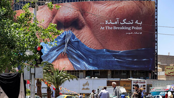 Motorists drive past a political billboard featuring US President Donald Trump and the Strait of Hormuz along Valiasr Square in Tehran on May 26, 2026.