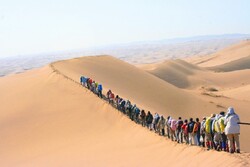 File photo shows trekkers hiking across the sun-scorched Maranjab Desert in central Iran