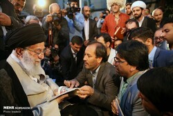 Leader of the Islamic Revolution Ayatollah Seyyed Ali Khamenei glances at a book by Tehran-based Afghan writer Mohammad-Sarvar Rajai (C) during his annual meeting with poets and literati on May 20, 20