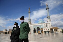 A couple wearing protective face masks, following the outbreak of coronavirus disease (COVID-19), walks on the street opposite a congregational mosque in Qom, Iran March 24, 2020. (Photo: WANA)