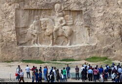 File photo depicts people visiting a magnificent Sassanid-era bas-relief in Naqsh-e Rustam, an ancient necropolis near Persepolis in Fars province, southern Iran.