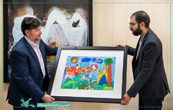 IIDCYA Public Relations and International Affairs Department director Hamed Rahnama (L) presents a painting by an IIDCYA member to the Iranian cultural attaché in Greece, Mehdi Nik-khah Qomi during a