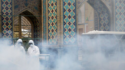 In this file photo, health workers spray disinfectant outside the Imam Reza shrine (AS) in Mashhad, northeast Iran on February 27, 2020. (Credit: WANA News Agency via Reuters)