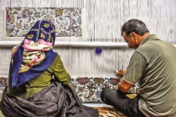 A couple weaves a carpet with specific pattern on an old loom installed at their home in the small village of Jiria, Farahan county, central Markazi province, on July 9, 2020.