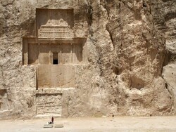A traveler looks at a massive rock-hewn tomb where a Persian Achaemenid king is laid to rest at the necropolis of Naqsh-e Rostam in southern Iran.