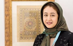 Iranian illuminator Zeinab Shahi poses with one of her works at the 22nd Sharjah Islamic Arts Festival, January 2020. (Islamic Art Magazine)  