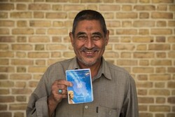 Afghan refugee Abdulrahim Rostami, 66, holds his health insurance booklet in Tehran, Iran. 