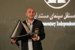 Filmmaker Sam Kalantari poses after accepting a lifetime achievement award during the 12th Independent Celebration of Iranian Documentary Cinema at the Iranian House of Cinema on August 6, 2021. (IRNA