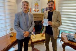 Iranian cartoonist Masud Shojaei-Tabatabai (R) holds his passport after getting a visa for Serbia from Serbian Ambassador Dragan Todorovic (L) in Tehran.