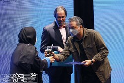 Mehdi Jafari (R) receives the award for best director for his drama “Yadoo” from director Puran Derakhshandeh during the 34th Isfahan International Film Festival for Children and Youth in Tehran on Oc