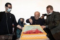 Artist Ali-Akbar Sadeqi cuts his 84th birthday cake at the Iranian Artists Forum on November 22, 2021.