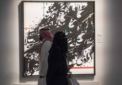 People pass a work by Iranian artist Mahsa Javad-Davachi, first place winner in the Modern Calligraphy category, during the Al Burda Festival at the Dubai Exhibition Center. (The National/Leslie Pable
