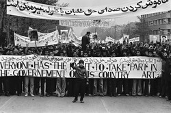 A photo by an anonymous photojournalist shows Iranian people taking part in an anti-government rally in 1979. They hold a banner reading Article 21 of the Universal Declaration of Human Rights