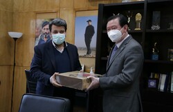 Cinema Organization of Iran director Mohammad Khazaei gives Chinese Ambassador Chang Hua a present at his office in Tehran on February 14, 2022.
