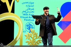 An artist holds his award during the closing ceremony of the 14th Fajr Festival of Visual Arts at Tehran’s Vahdat Hall on March 4, 2022. (Honaronline/Raha Ahmadi)