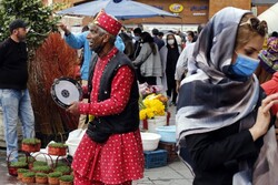  An Iranian man dressed as Haji Firouz, the traditional herald of Noruz, walks and collects money among the people shopping at a street market in Tehran in March 2021.