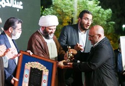 Painter Abdolhamid Qadirian (R) receives his award as the Islamic Revolution Artist of the Year from IIDO director Hojjatoleslam Mohammad Qomi during the 8th Islamic Revolution Art Week on April 15, 2