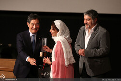 Photographer Maryam Raufimanesh (c) receives her prize from Japanese Ambassador Kazutoshi Aikawa during the 5 International Photo Award at the Film Museum of Iran on June 22, 2022. (Honaronline/Milad
