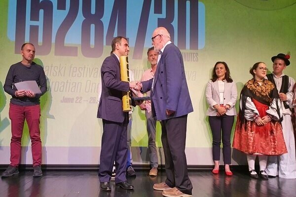 Iranian Ambassador Parviz Esmaeili (2nd L) shakes hands with jury president Vaclav Antonin Simek after receiving an award on behalf of an Iranian filmmaker at the Croatian One-Minute Film Festival in