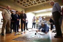 Visual Arts Office director Abdorreza Sohrabi (4th L) and his colleagues watch an artist creating a painting during an exhibition at Tehran’s Niavaran Cultural Center on July 15, 2022. (Honaronline)