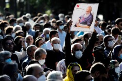 A man holds a picture of Amir-Hushang Ebtehaj at a gathering held in front of Tehran’s Vahdat Hall on August 26, 2022 to bid farewell to the renowned Persian poet. (ISNA/Amid Farahi)