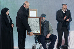 Director Jamal Shurjeh (C) accepts an award for his lifetime achievement during the 13th Ammar Popular Film Festival at Tehran’s Felestin Cinema on January 12, 2023. (Mehr/Saeidreza Razavi)