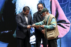 Photojournalist Mahmud Abdolhosseini (L) receives the Qalam-e Moqaddas from Culture Minister Mohammad-Mehdi Esmaeili at Tehran’s Rudaki Hall on February 1, 2023. (ISNA/Hadi Zand)