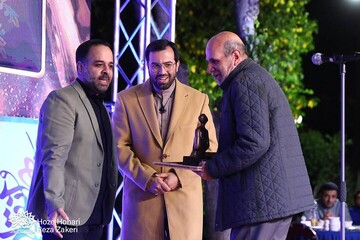 Photographer Seyyed Abbas Mirhashemi (R) receives the award for the Islamic Revolution Artist of the Year from Art Bureau deputy director Ali Foruzanfar (C) and his colleague Ehsan Baqeri (L) on April