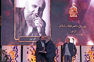 Graphic designer Masud Nejabati (C) accepts an award for the Islamic Revolution Artist of the Year during the closing ceremony of the Islamic Revolution Art Week in Tehran on April 15, 2023. (Art Bure