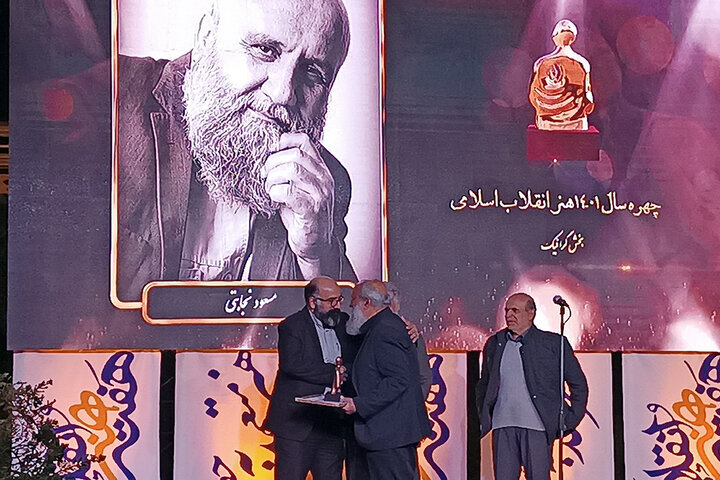 Graphic designer Masud Nejabati (C) accepts an award for the Islamic Revolution Artist of the Year during the closing ceremony of the Islamic Revolution Art Week in Tehran on April 15, 2023. (Art Bure
