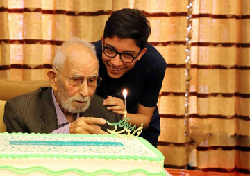 Litterateur Mohammad-Ali Movahhed blows the candle of his 100th birthday cake at a party held at the Academy of Persian Language and Literature in Tehran on May 22, 2023. His grandchild is also seen i