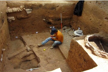 File photo depicts an archaeologist sitting inside a trench carved within the Saqqez region of Kordestan province, western Iran.