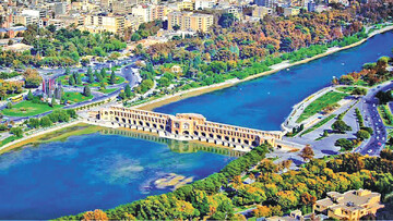 An aerial view of modern Isfahan with a 17th-century arch bridge constructed over Zayanderood seen in the foreground.