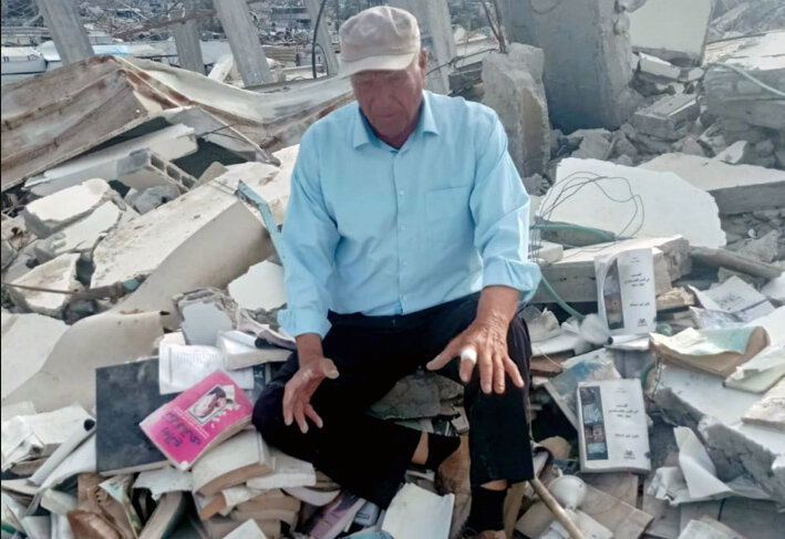 Dr. Fayez Abu Shamala is sitting between his books on the ruins of his destroyed house in Khan Yunis. He says, “The house and everything we have are sacrifices for the soil of the homeland and for the Al-Aqsa Mosque. The Palestinian people will not be defeated, and victory is ours, God willing.”