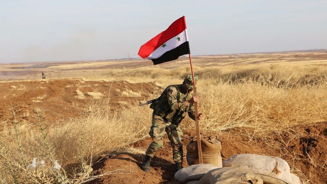 A Syrian solider raises national flag