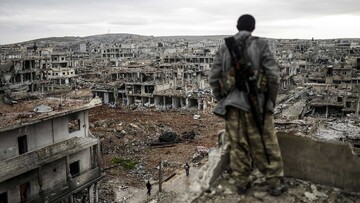 A Syrian soldier overlooking war devastation