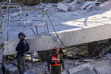 An officer from the Israeli military's home front command (right) and a police officer examine the damage after shrapnel from a Yemeni missile collapsed a building in the Tel Aviv suburb of Ramat Gan,