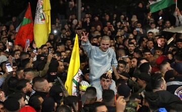 Large number of Palestinian people welcome a freed prisoner carried on the shoulder of a man