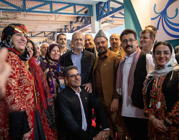 Iranian President Masoud Pezeshkian (c), encircled with a number of exhibitors and travel insiders, poses for a photo in the early hours of the 18th Tehran International Tourism and Related Industries Exhibition, February 11, 2025.