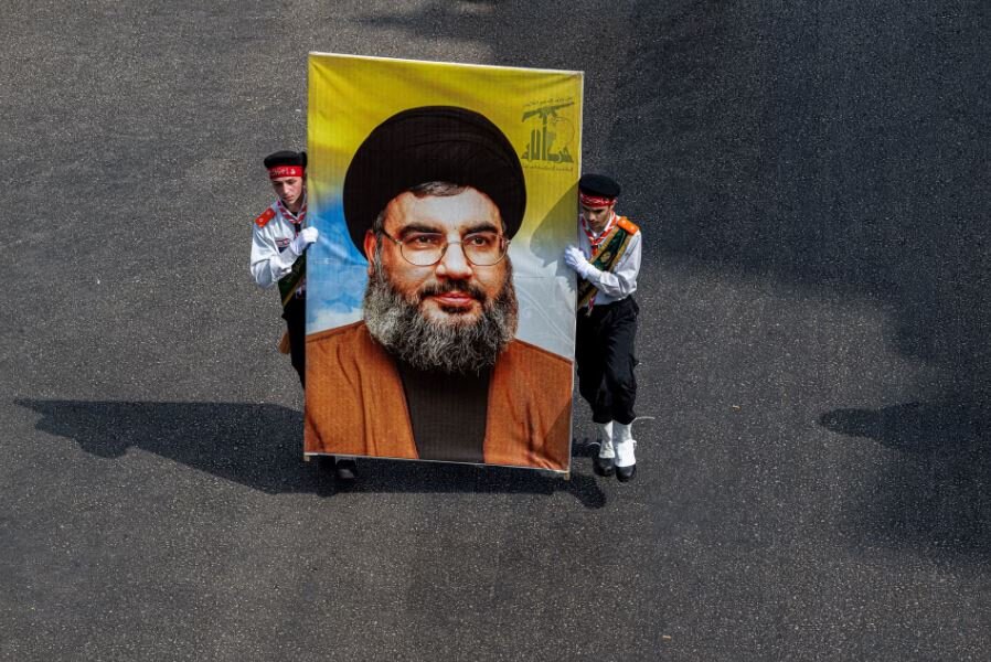 Two teenagers carry a big photo of Nasrallah