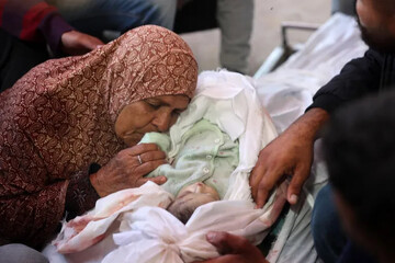 A Palestinian woman bids her grandson Tamer farewell in Deir el-Balah in the central Gaza Strip, after he was killed along with his mother in an Israeli strike [File: Eyad Baba/AFP]