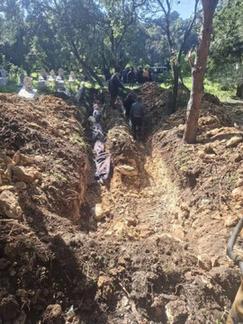 Bodies are laid in a mass grave in Pine village