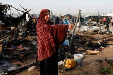 A Palestinian woman gestures as people inspect the site of an Israeli strike on a tent camp housing displaced people, in the al-Mawasi designated ‘safe zone’, in Khan Younis in the southern Gaza Strip